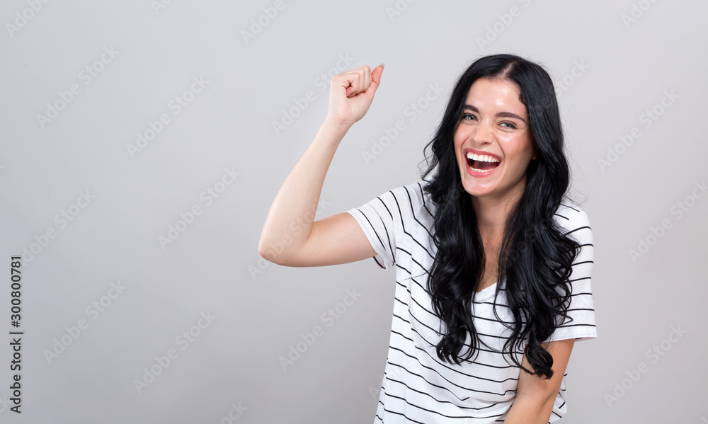 Young woman making a yay gesture on a gray background