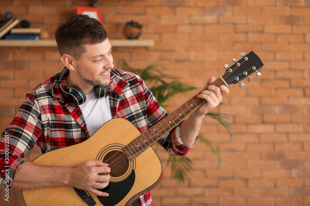 Handsome man playing guitar at home