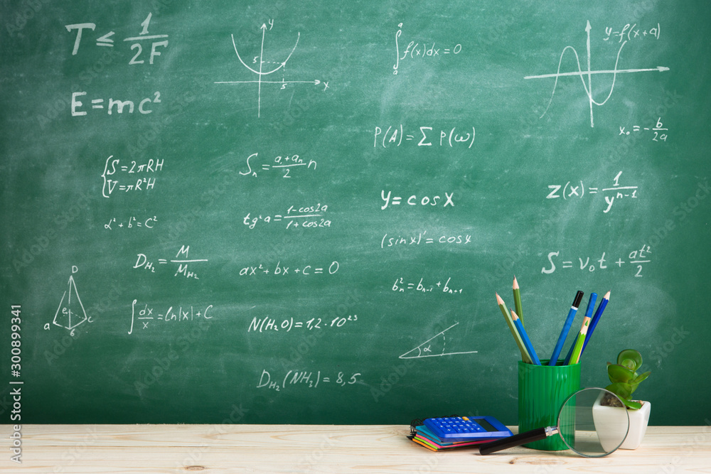 Education concept - school supplies on the desk in the auditorium, blackboard background