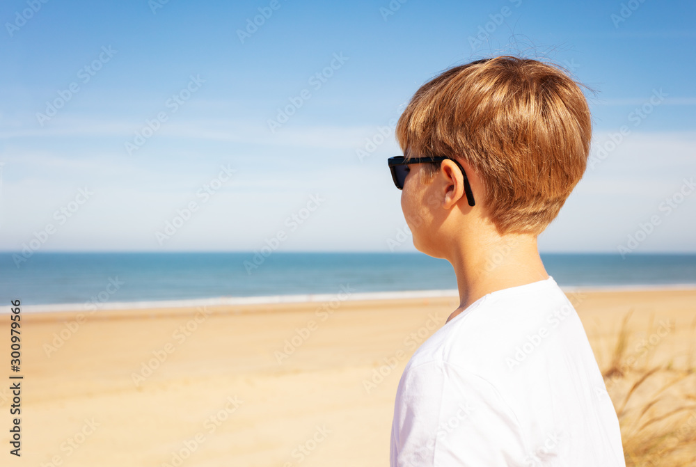 Handsome boy on the sand beach looking at see