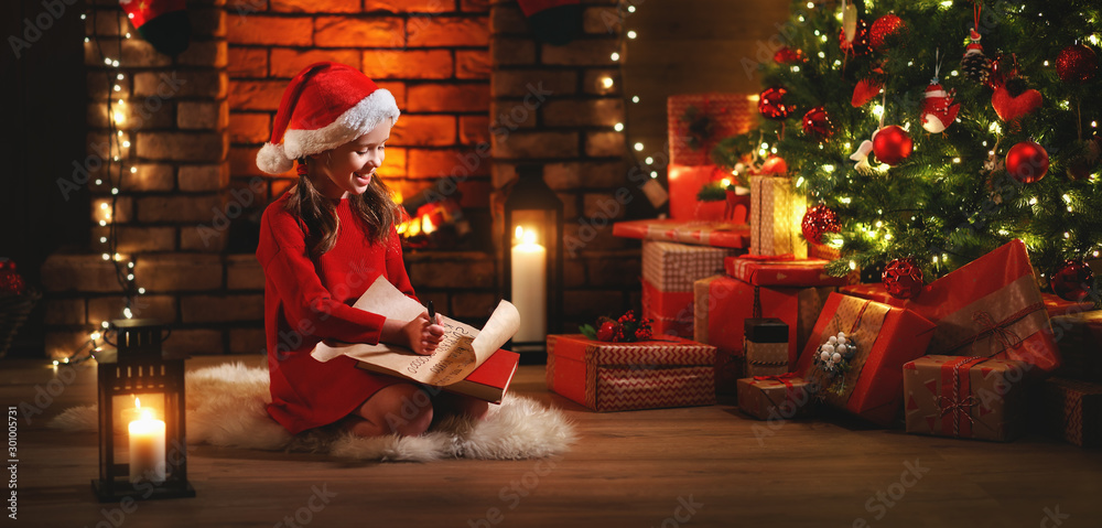 happy child girl writing letter santa home near Christmas tree.