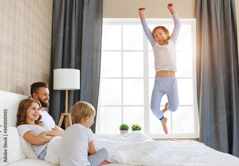 happy family mother, father and children laughing, playing, fights pillows and jumping in bed   at h