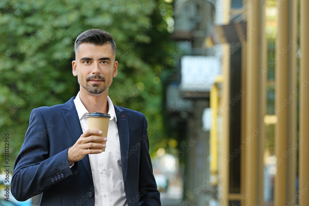 Portrait of handsome businessman with cup of coffee outdoors