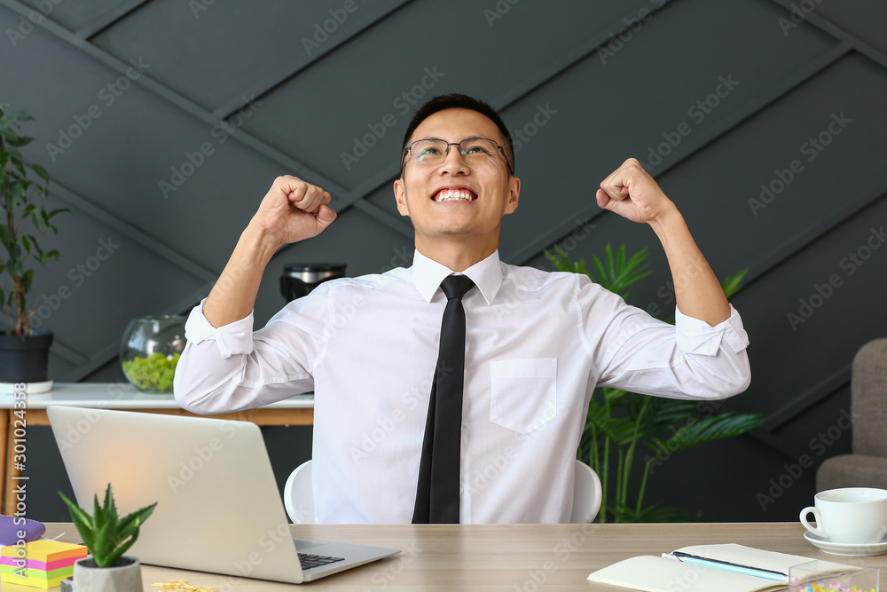 Happy Asian businessman at table in office