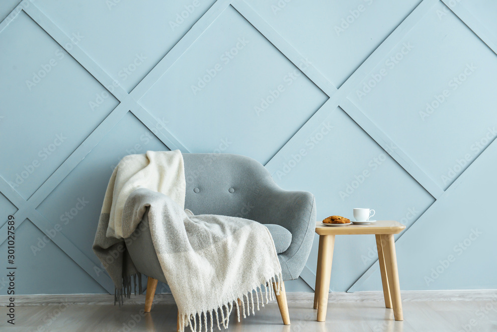 Armchair and table near grey wall in room