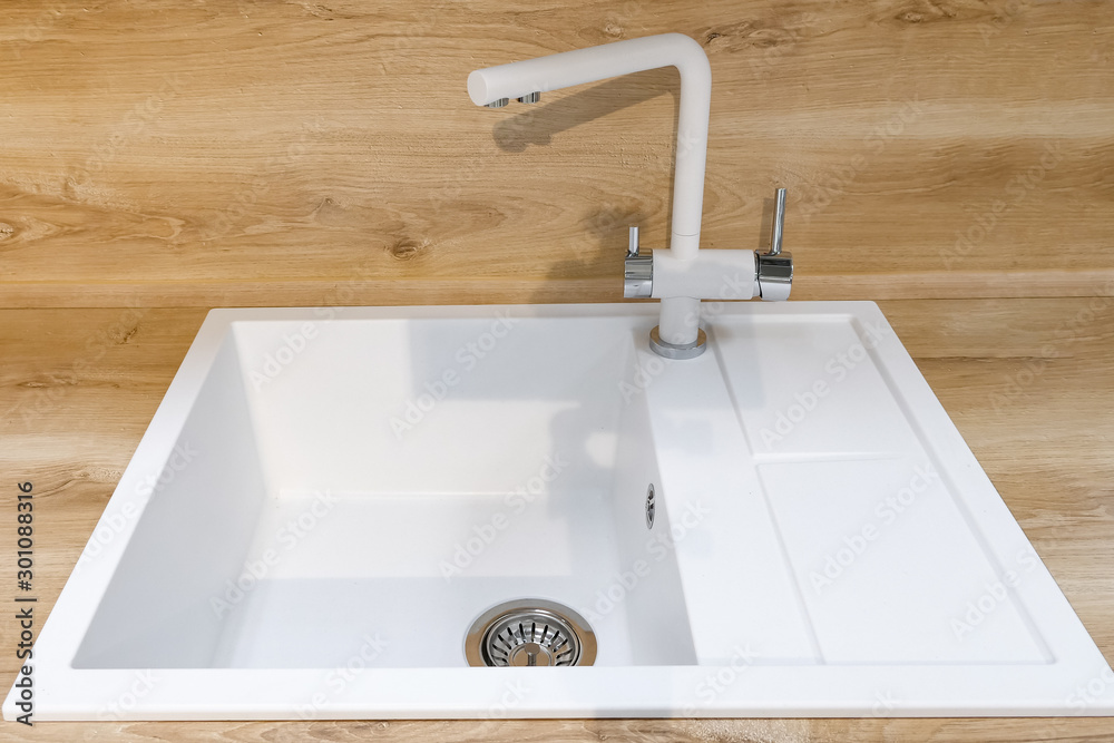 modern white square sink with water tap located on smooth wooden kitchen set surface, closeup