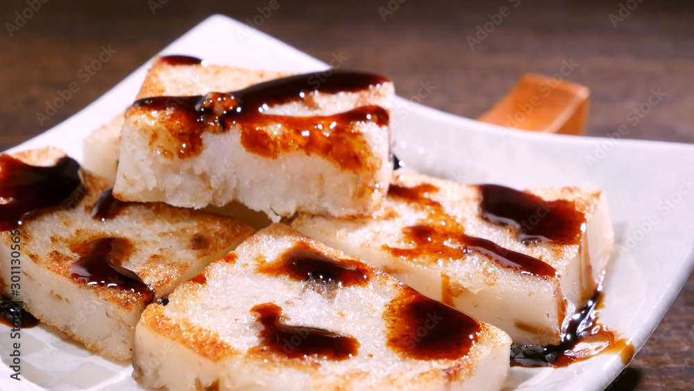 Pouring black soy sauce on ready-to-eat delicious turnip cake, Chinese traditional local dish radish