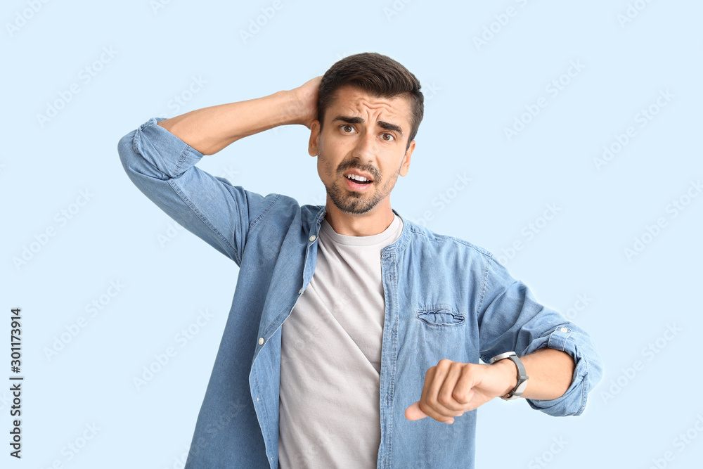 Stressed man with wrist watch on light background