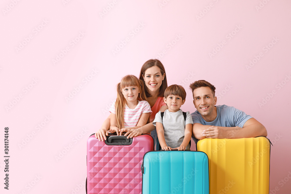 Happy family with luggage on color background