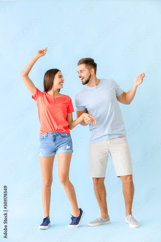 Portrait of dancing young couple on color background