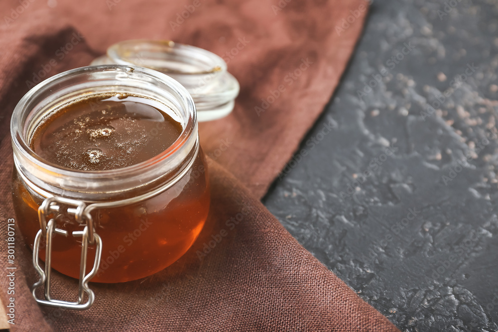 Jar with tasty honey on dark background