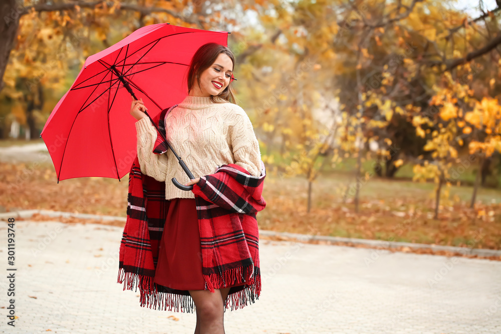 Stylish young woman with umbrella in autumn park