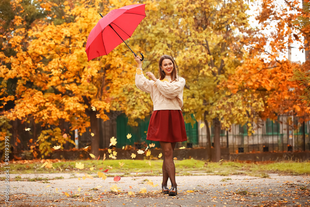 Stylish young woman with umbrella in autumn park