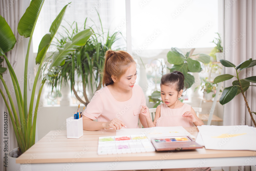 Asian pretty young mother and her daughter paining the plaster doll together.