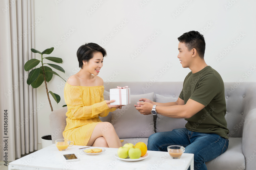 love, holiday, celebration and family concept - smiling man surprises his girlfriend with present at