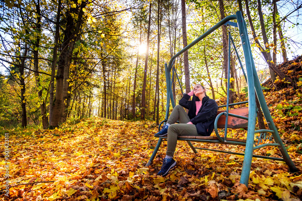 Young woman on swing in beautiful autumn forest