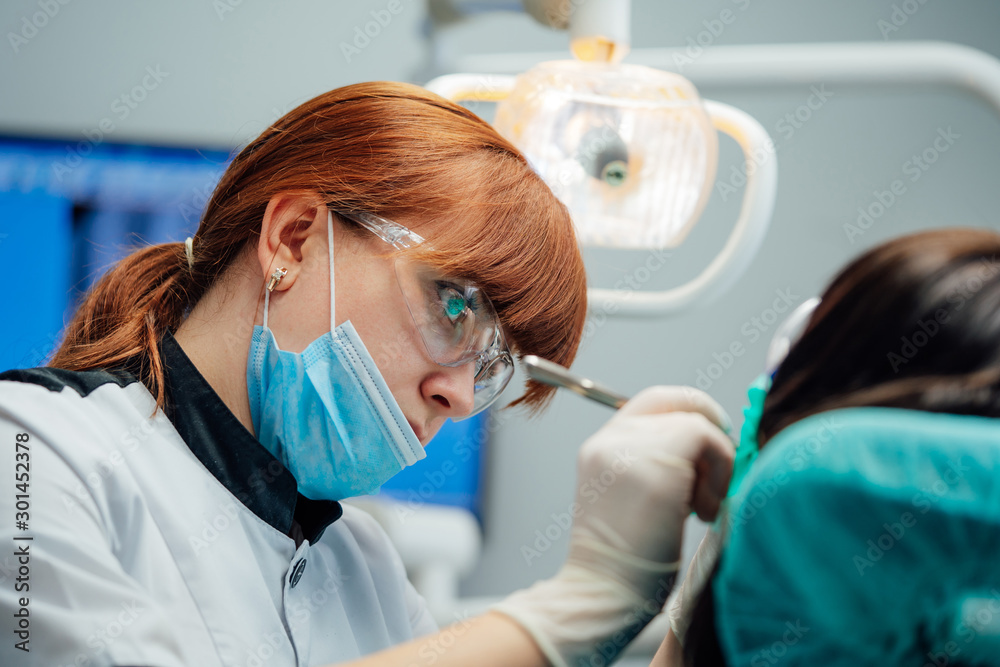 Young female stomatologist treating patients teeth. Healthy teeth concept. Selective focus.