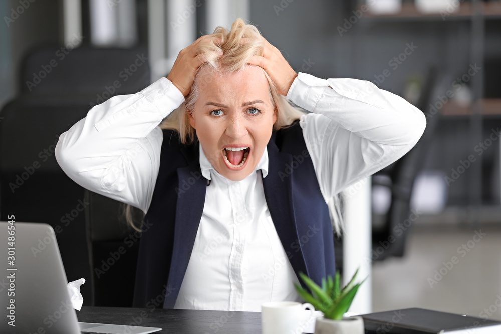 Angry mature woman working in office