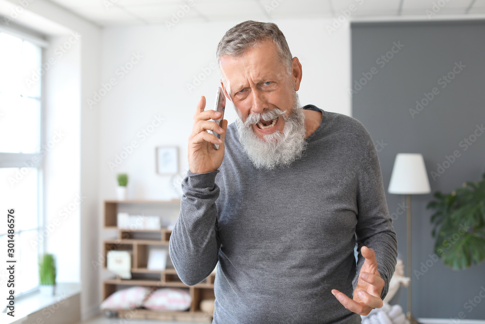 愤怒的成熟男人在家用手机聊天