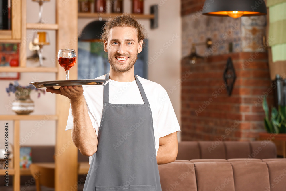 餐厅年轻男服务员端着一杯葡萄酒