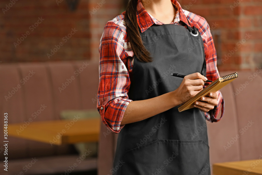 餐厅里拿着笔记本的年轻女服务员，特写