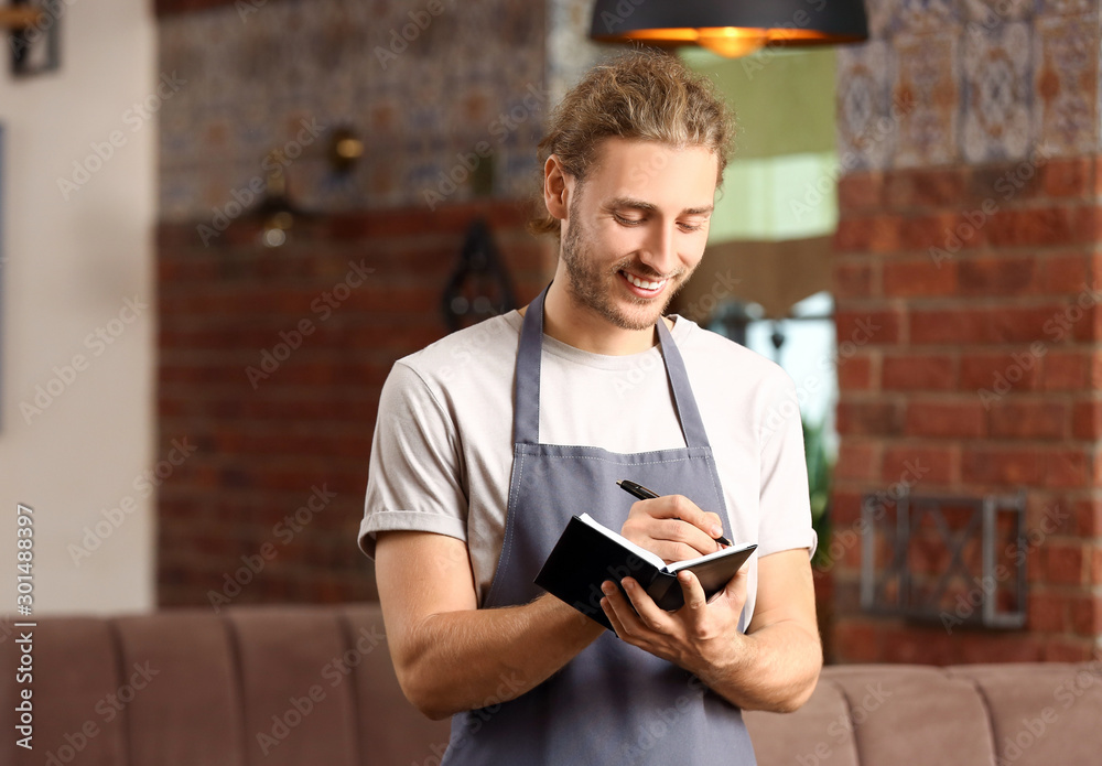 Young male waiter in restaurant