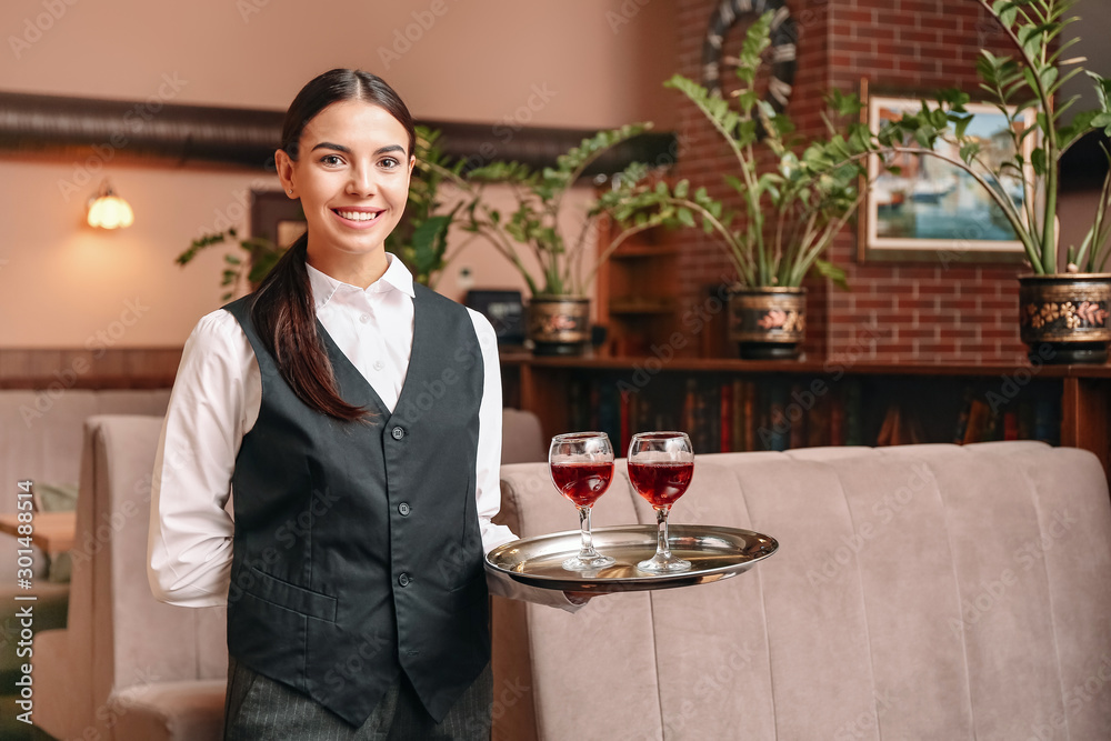 餐厅里年轻的女服务员端着几杯葡萄酒