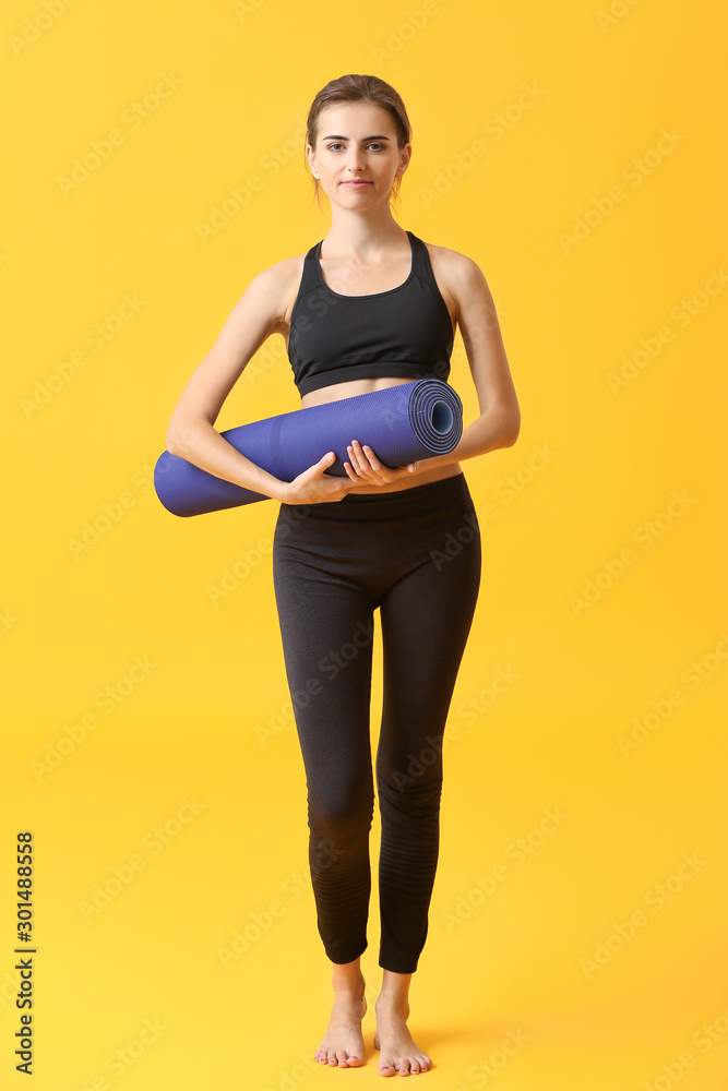 Beautiful young woman with yoga mat on color background