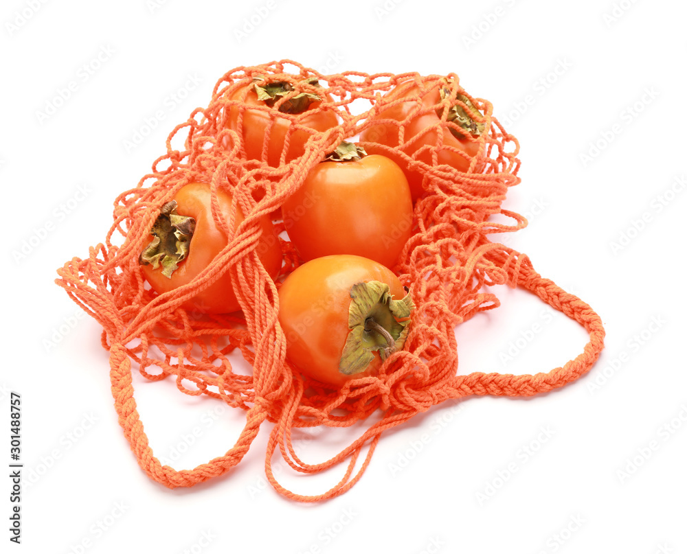 Bag with ripe persimmons on white background