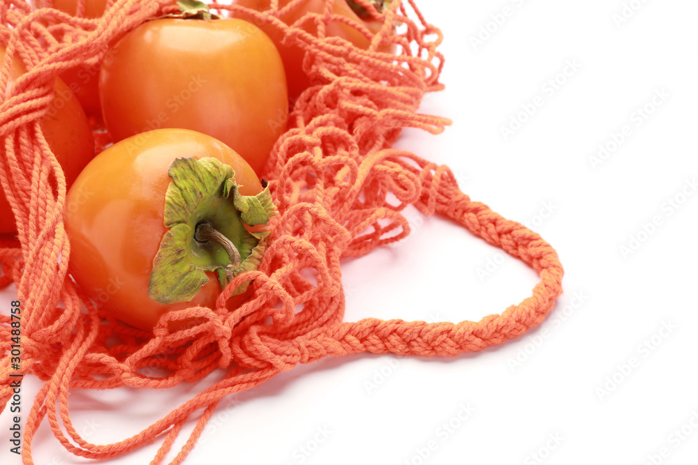 Bag with ripe persimmons on white background