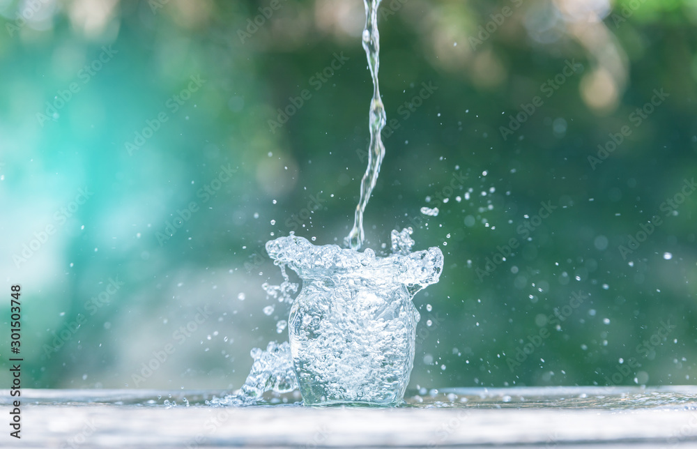 Water splash in glass Select focus blurred background.Drink water pouring in to glass over sunlight 