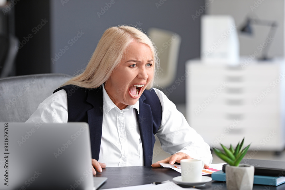 Angry mature woman working in office