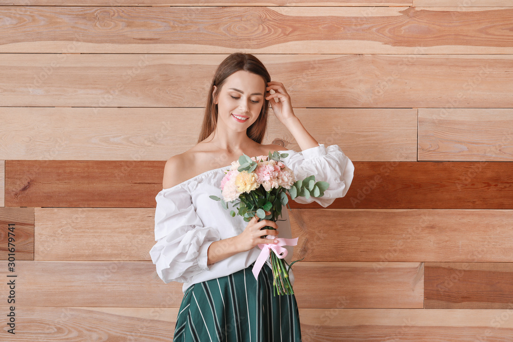 Beautiful young woman with bouquet of carnation flowers on wooden background