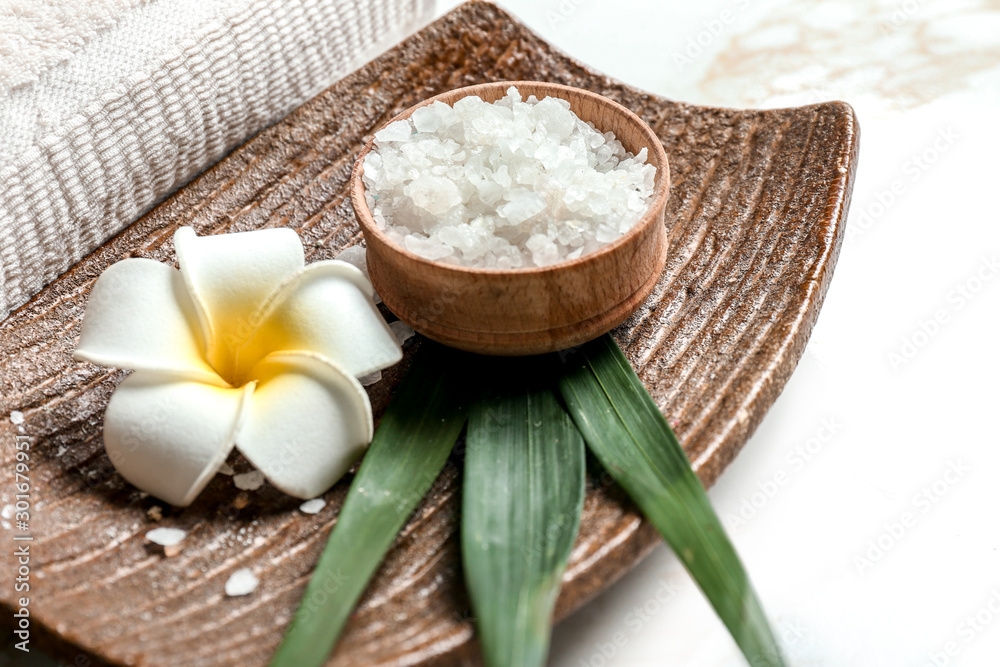 Plate with sea salt and flower on light background, closeup