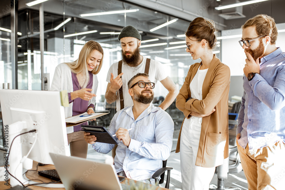 Senior manager having a meeting with office workers standing together near the working place in the 