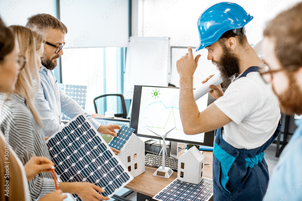 Group of alternative energy engineers discussing a project with a worker during a meeting in the off