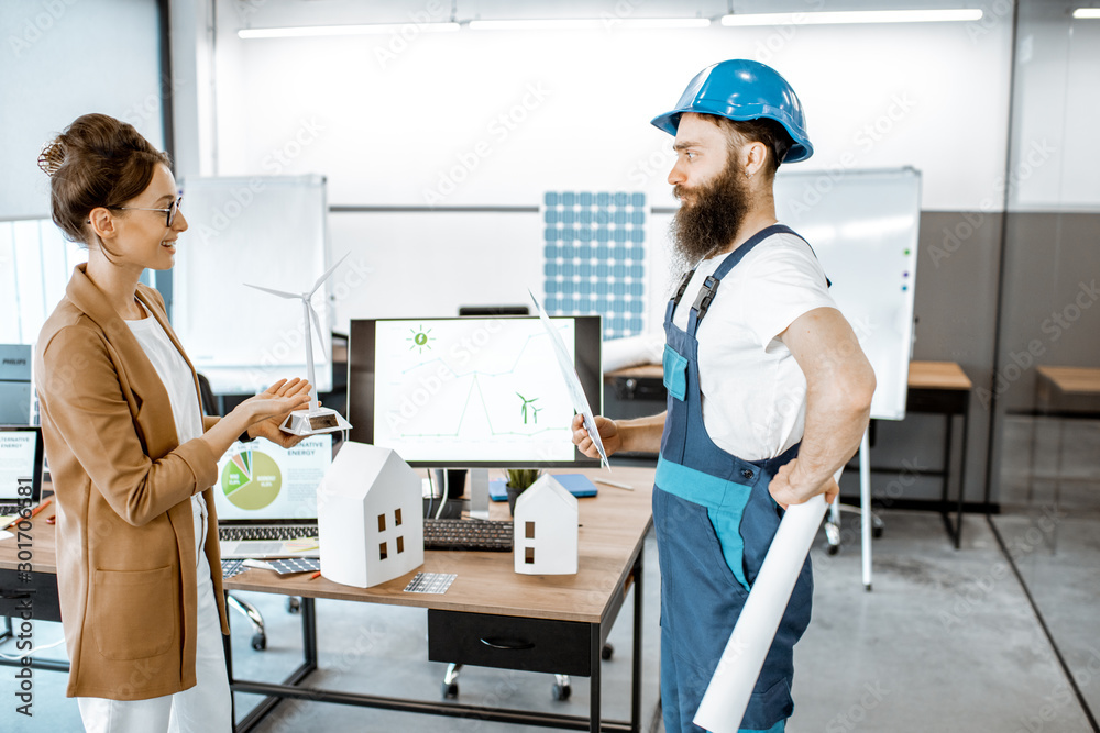 Male worker and woman engineer working on a project of alternative energy, holding wind turbine mode