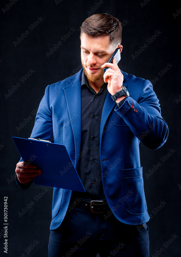 Happy businessman talking on the phone with folder in hand isolated over white background in studio 