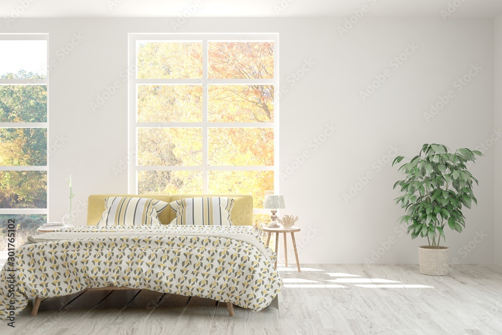 White stylish minimalist bedroom with armchair and autumn landscape in window. Scandinavian interior