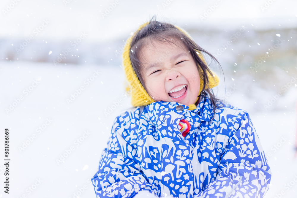 快乐的亚洲小女孩在下雪的冬天玩雪球。