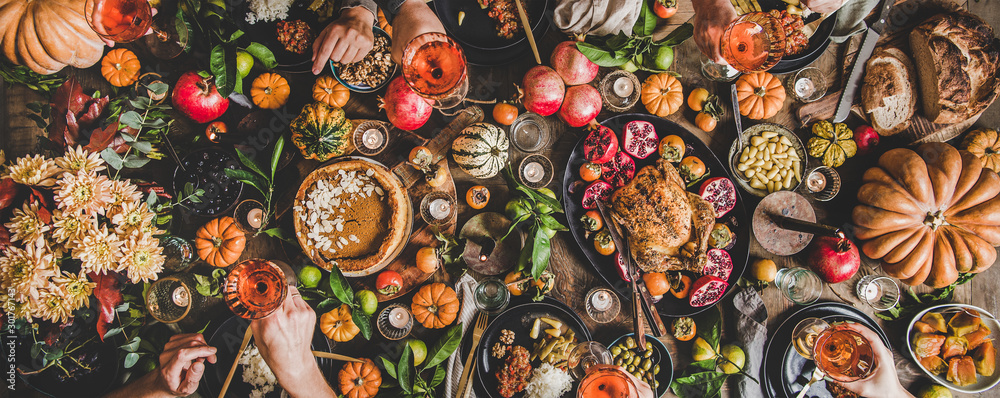 Family celebrating at Thanksgiving table. Flat-lay of feasting peoples hands with glasses of wine ov