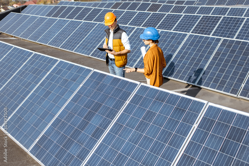 Two engineers or architects examining the construction of a solar power plant, standing with digital