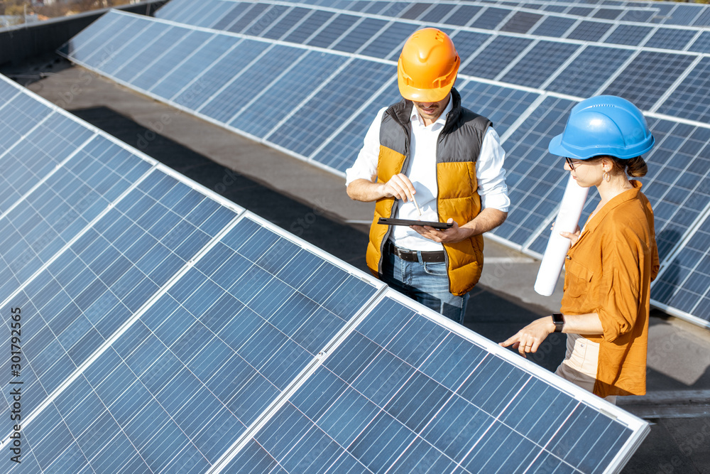 Two engineers or architects examining the construction of a solar power plant, standing with digital