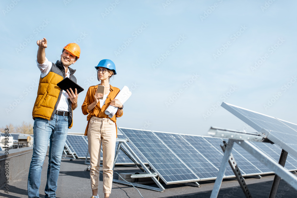 Two engineers or architects examining the construction of a solar power plant, walking with digital 