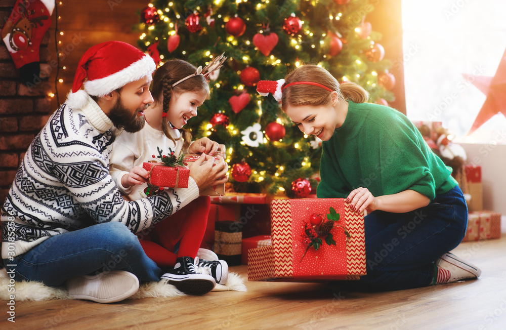 happy family mother, father and child  with gifts near   Christmas tree at home.