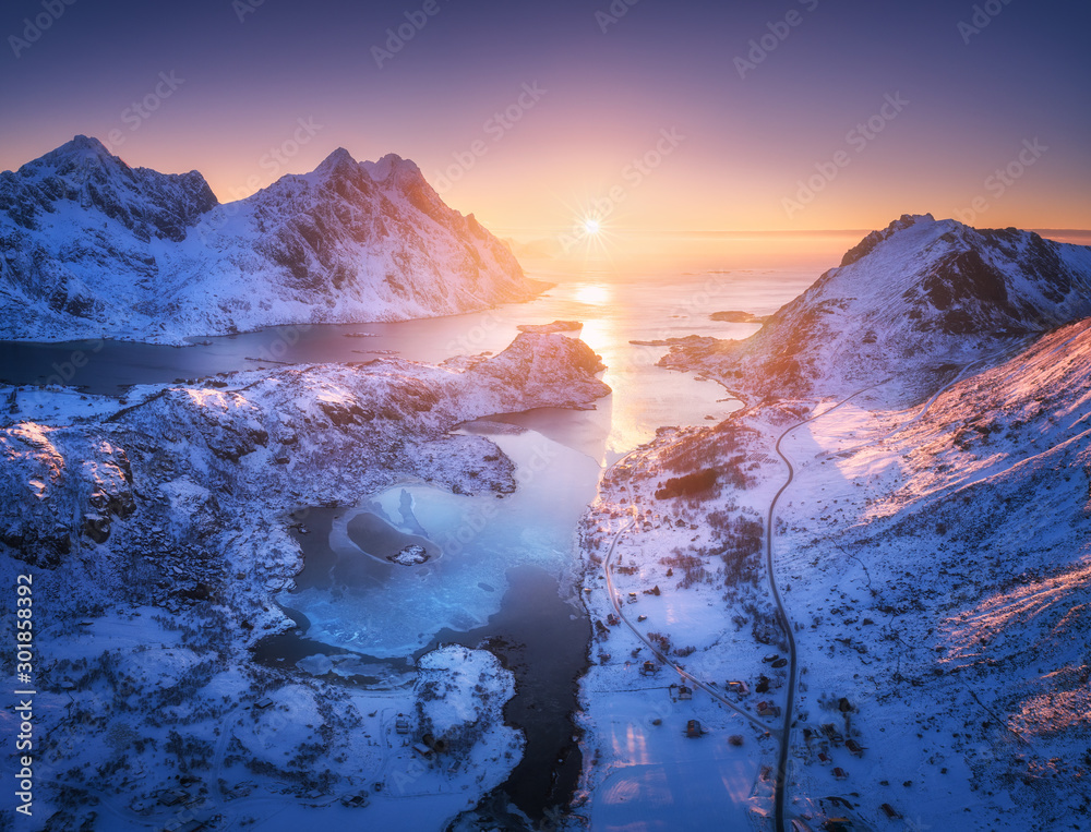 挪威罗弗敦群岛日落时的雪山、大海和紫色天空的鸟瞰图。冬季色彩