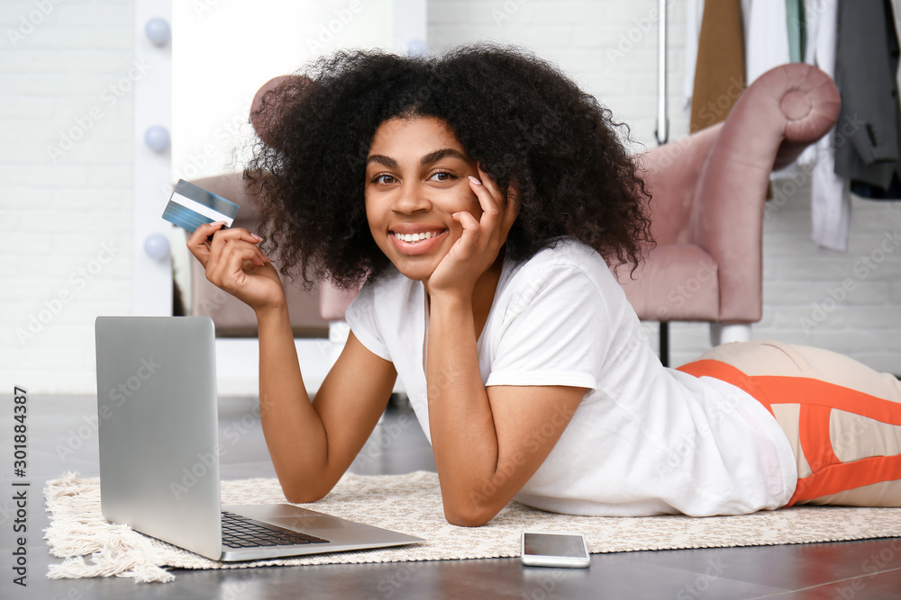 Beautiful African-American woman using laptop for online shopping at home