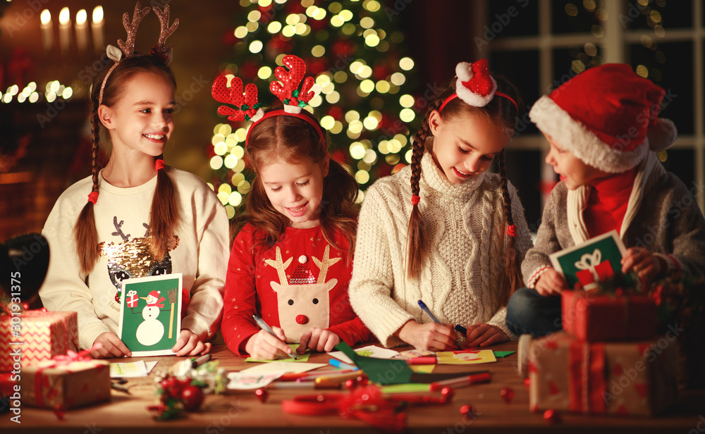 happy friends kids draw decorations and write  letter to Santa near Christmas tree