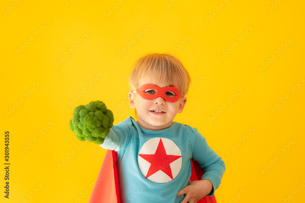 Superhero child holding broccoli