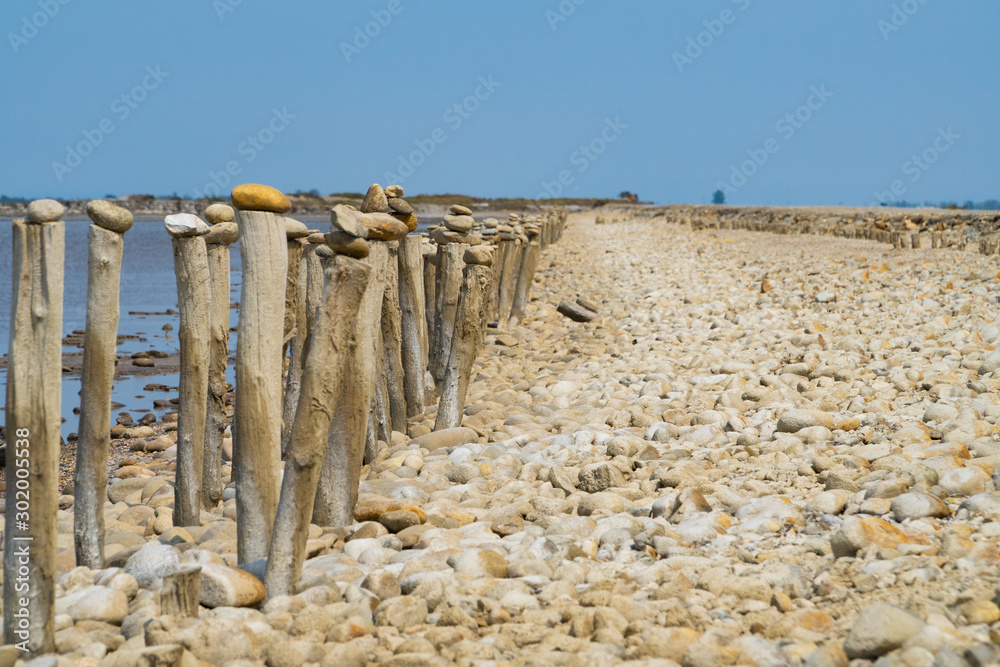 A row of wooden columns near the sea, the blue sky in the back